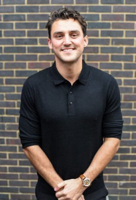 Cameron of London Tax Bureau, standing in front of a brick wall